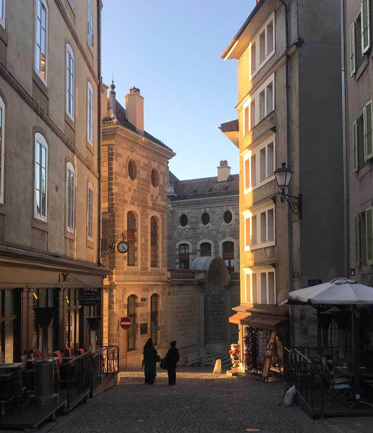 Sunset streets, Geneva - friends pause for an impromptu conversation in the winter light, reflecting the slower social pace and rhythms of the Old Town.
